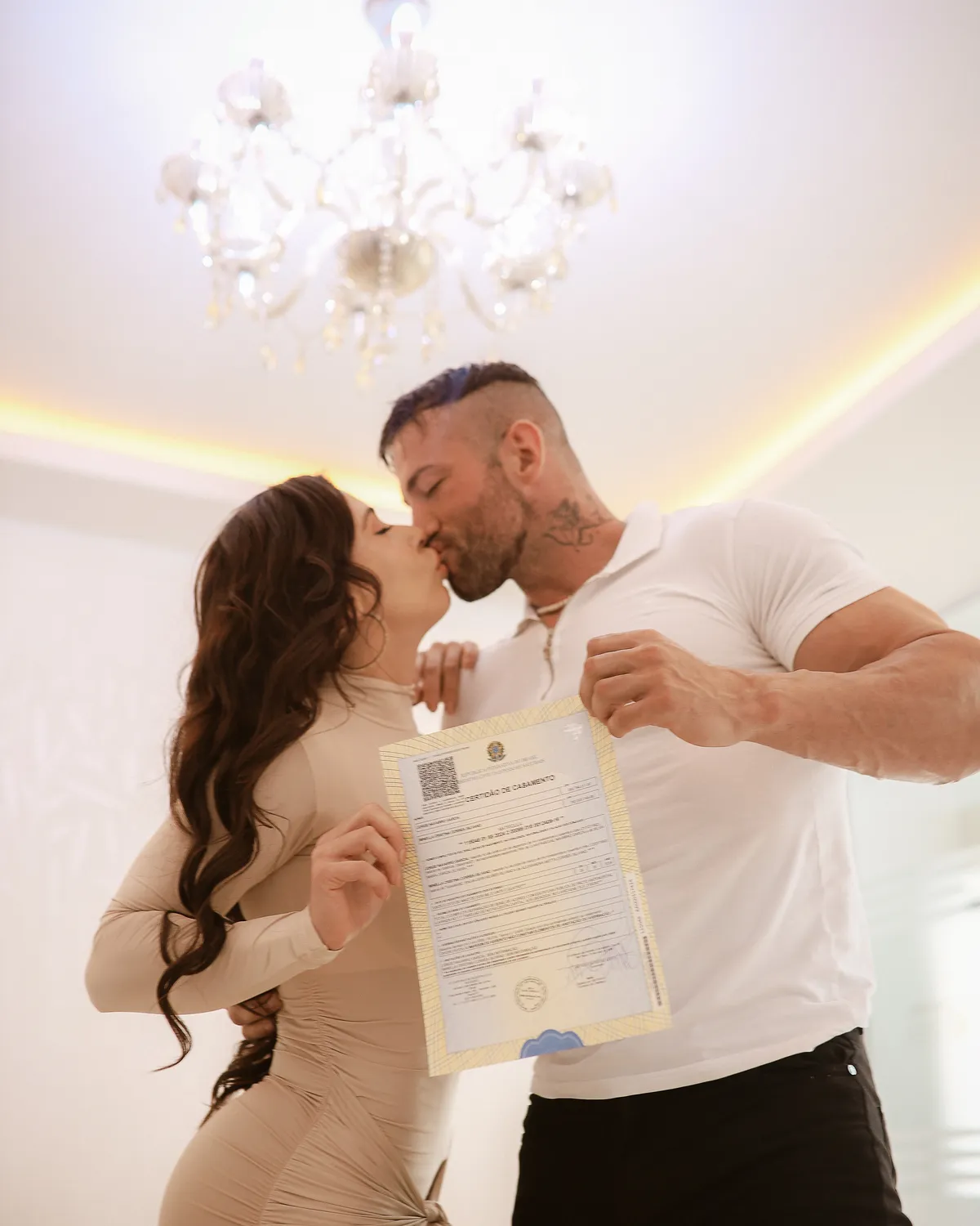 Maximo Garcia con una mujer en una habitación luminosa, sosteniendo un documento firmado